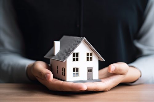 woman showing with one hand a mini house. Real state concept.